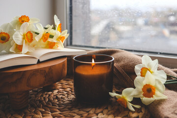 Candle and daffodils on the windowsill, spring composition