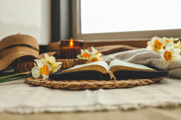 Obraz na płótnie Canvas Open Bible with flowers and candles in a cozy home interior. Christian beautiful morning photography.
