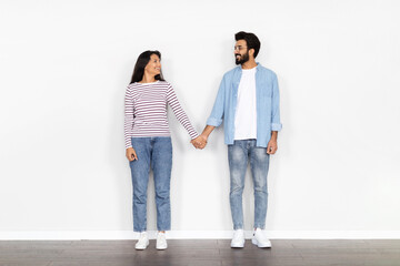 Cheerful loving eastern spouses posing at new empty house