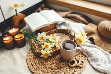 Spring still life, cup of tea, candles, open book and hat