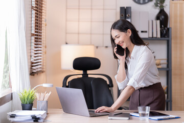 Young happy businesswoman working with tablet and mobile phone in corporate office.