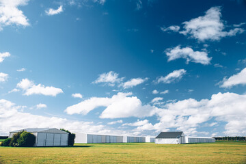 Steel barn on a farm with cloudy blue sky.