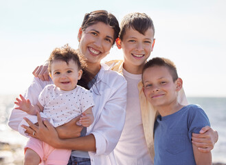 Mother with her adopted children Portrait of multiethnic family on the beach. Happy family on holiday by the ocean. Young mother on the beach with her children. Two adoptive boys with their family