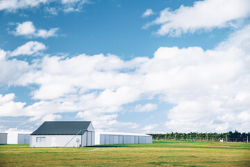 Steel barn on a farm with cloudy blue sky. - 596763051