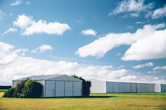 Steel barn on a farm with cloudy blue sky.