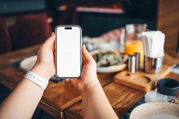 Girl holding a phone with a blank screen in a cafe, with food in the background