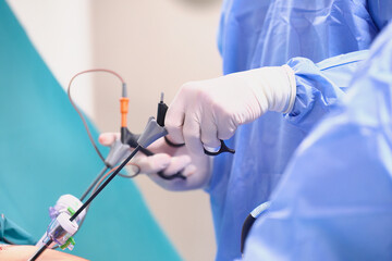 Operacja laparoskopowa na sali operacyjnej w szpitalu. Dłonie chirurga w sterylnych rękawiczkach trzymają narzędzia endoskopowe. Asysta instrumentariuszki.