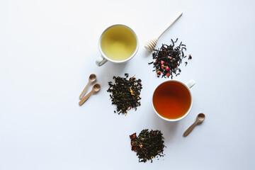 Herbal leaf dried tea and cups with drink, top view on white background