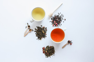 Herbal leaf dried tea and cups with drink, top view on white background