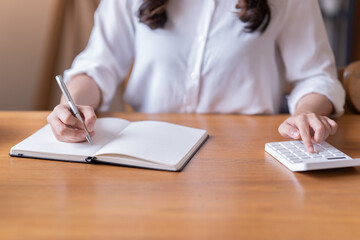 Attractive happy young Asian businesswomen at home, sitting at the desk, using a laptop computer, tablet and headphones having a video chat.