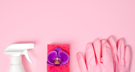 Spring cleaning concept. Detergent, orchid flower, kitchen sponge and rubber gloves on a pink background. Flatlay. Banner. Copy space. Top view.