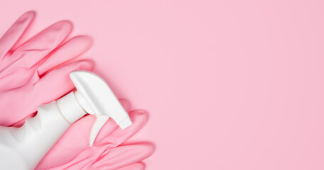 Obraz na płótnie Canvas Pink rubber gloves and spray cleaner on a pink background. Flatlay. Banner. Close-up. Top view. Place for text.