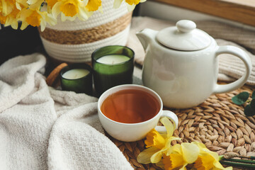 Obraz na płótnie Canvas Cup of tea, candles, basket with daffodils, spring aesthetic photo