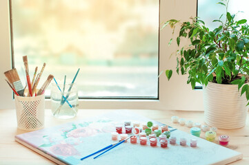 drawing, home hobby, a set of paint brushes and a picture by numbers on the table near the window. High quality photo