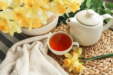 Cup of tea, candles, basket with daffodils, spring aesthetic photo