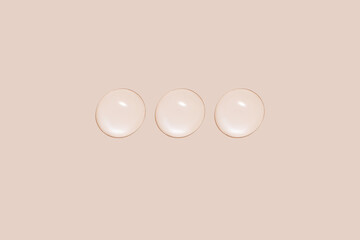 Drops of transparent gel or water in a row. On a beige background.