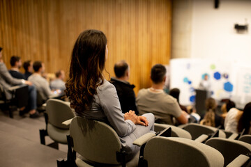 Young woman sitting in audience on conference or workshop