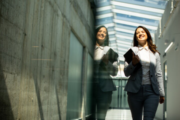Young woman walking with digital tablet in the office hallway