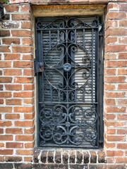 antique iron security gate over a window set in a red brick building