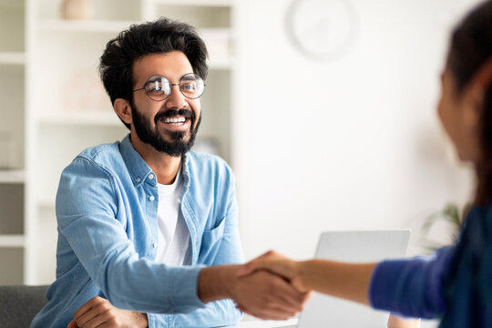 Partnership Concept. Smiling Indian Male Entrepreneur Giving Hand For Handshake To Female