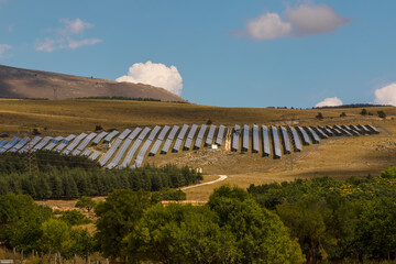 Blue photovoltaic solar panel system producing clean renewable energy over rural landscape in Italy Europe. Renewable energy offers a good example of green resilience