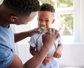 Dads showing me how to brush properly. Shot of a father brushing his sons teeth in the bathroom at...