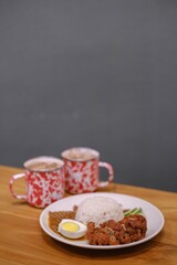 Portrait or vertical shot of a plate of Nasi Lemak with two mugs of tea. Blurred background