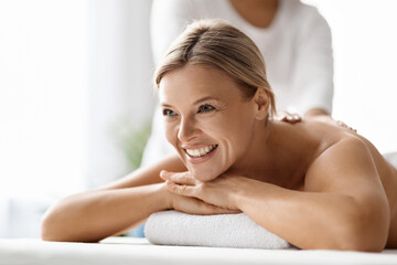 Fototapeta premium Closeup of beautiful middle aged woman enjoying back massage at spa salon