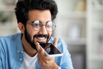Closeup Shot Of Happy Indian Man Recording Voice Message On Smartphone