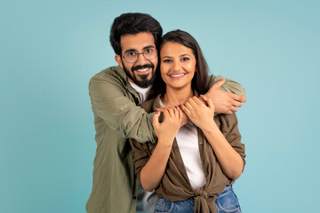 Beautiful young indian couple posing on blue studio background