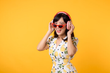 Smile pretty asian model person listen music song and enjoy dance with wireless headphone online audio radio sound. Positive fun exited joyful youth female woman on yellow isolated background studio