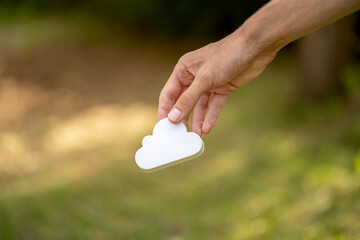 Man holding a simple white cloud symbol in hand, cloud computing and storage services sign held in...