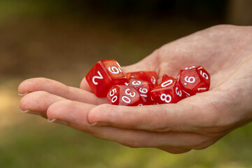 Man holding a group of simple red classic RPG game dice, objects held in hand detail, closeup Role...