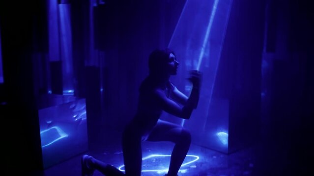 sport workout in gym with enigmatic blue light and laser rays, sexy female figure in darkness