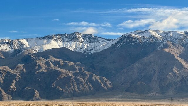 Snow capped mountains, with scrubland desert in foreground, seen from freeway near Lone Pine, California