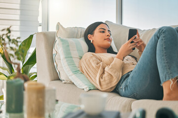 Her idea of the perfect day off. Shot of an attractive young woman texting while chilling at home.