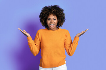 Emotional amazed young black woman gesturing on purple