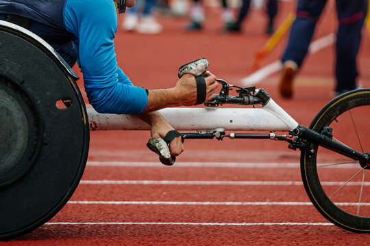 close-up racing wheelchair with male athlete, hands in racing gloves, summer para athletics championships