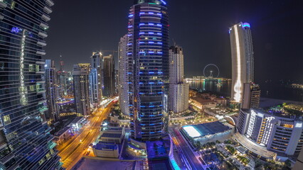 Fototapeta premium Panoramic view of the Dubai Marina and JBR area and the famous Ferris Wheel aerial night timelapse