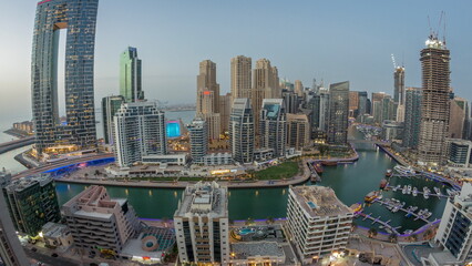 Panoramic view of Dubai Marina with several boat and yachts parked in harbor and skyscrapers around...