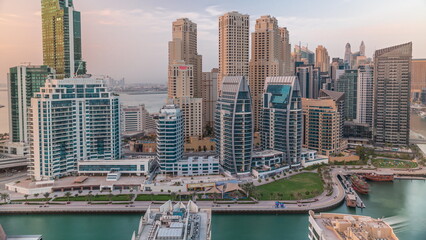 Obraz premium Dubai Marina with several boat and yachts parked in harbor and skyscrapers around canal aerial timelapse.