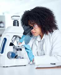 One beautiful young african american woman with an afro wearing a labcoat and looking at medical...
