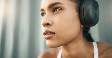 Closeup of one fit young hispanic woman listening to music with headphones while exercising in an...