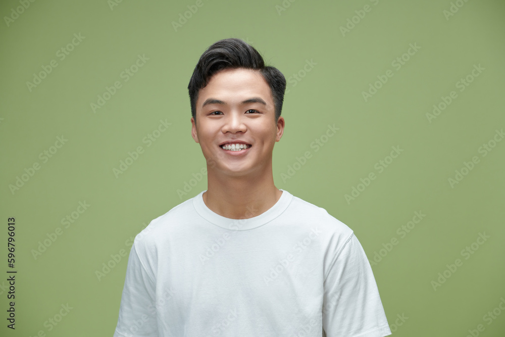 Wall mural Handsome portrait of young Asian man smiling isolated on light green background