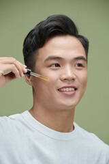 Young man using serum for skin care