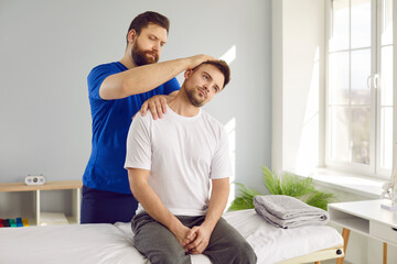 Man professional osteopath examining young man in modern hospital office. Chiropractor helping man...