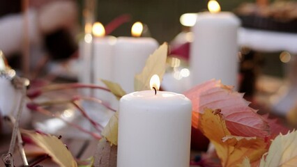 Beautiful Thanksgiving festive fall table setting with white burning candles and autumn leaves close up. Blurred background with eating child and homemade pie on stand. Family celebration dinner. - Powered by Adobe