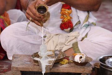 Performing Pooja for Hindu god siva linga with milk, honey and coconut water