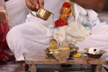 Performing Pooja for Hindu god siva linga with milk, honey and coconut water