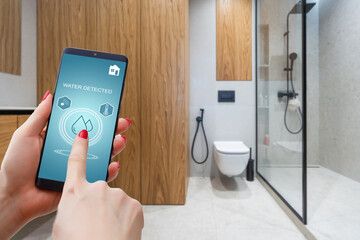 Hand holding smart phone with home control application with water detected, Smart home concept.